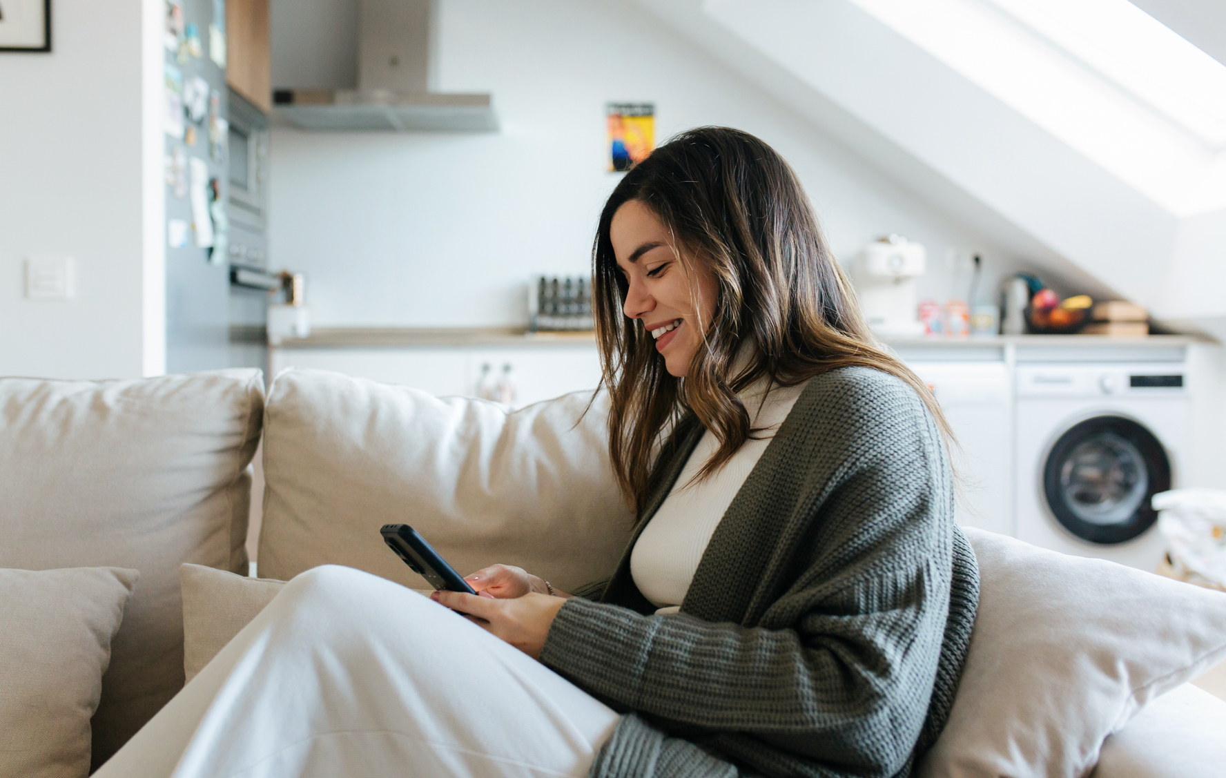 A renter smiling at her phone on the couch in her apartment